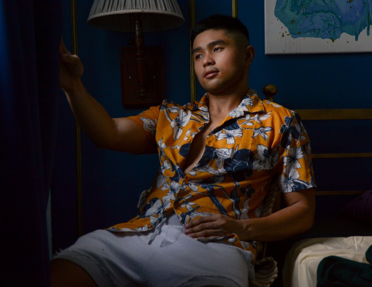 man in yellow and white floral button up shirt sitting on chair