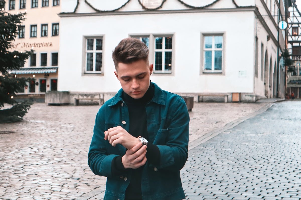 man in black coat standing on sidewalk during daytime