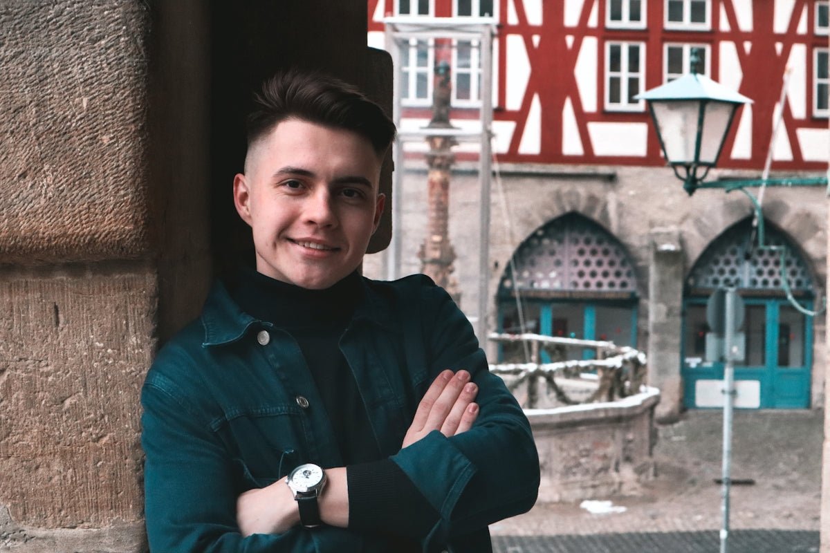 man in blue button up long sleeve shirt standing near brown concrete building during daytime