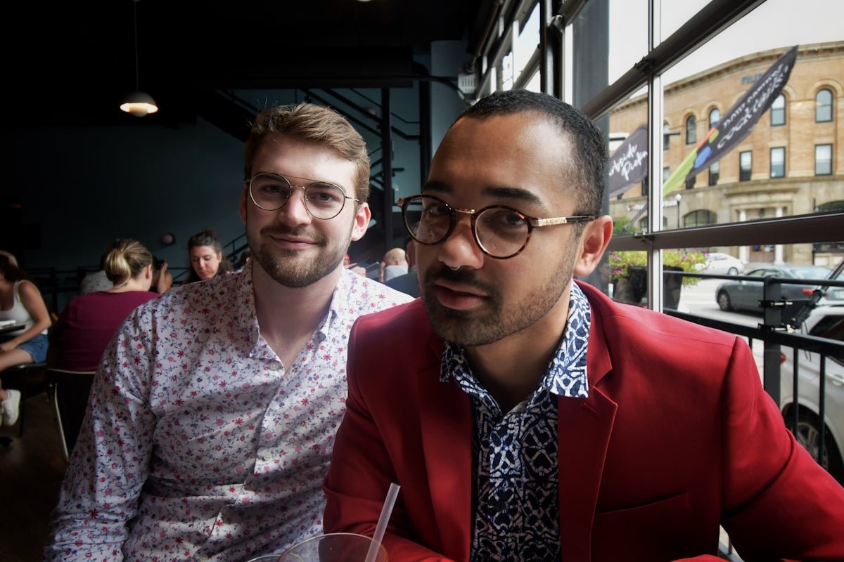 man in red suit jacket beside woman in white and purple floral dress