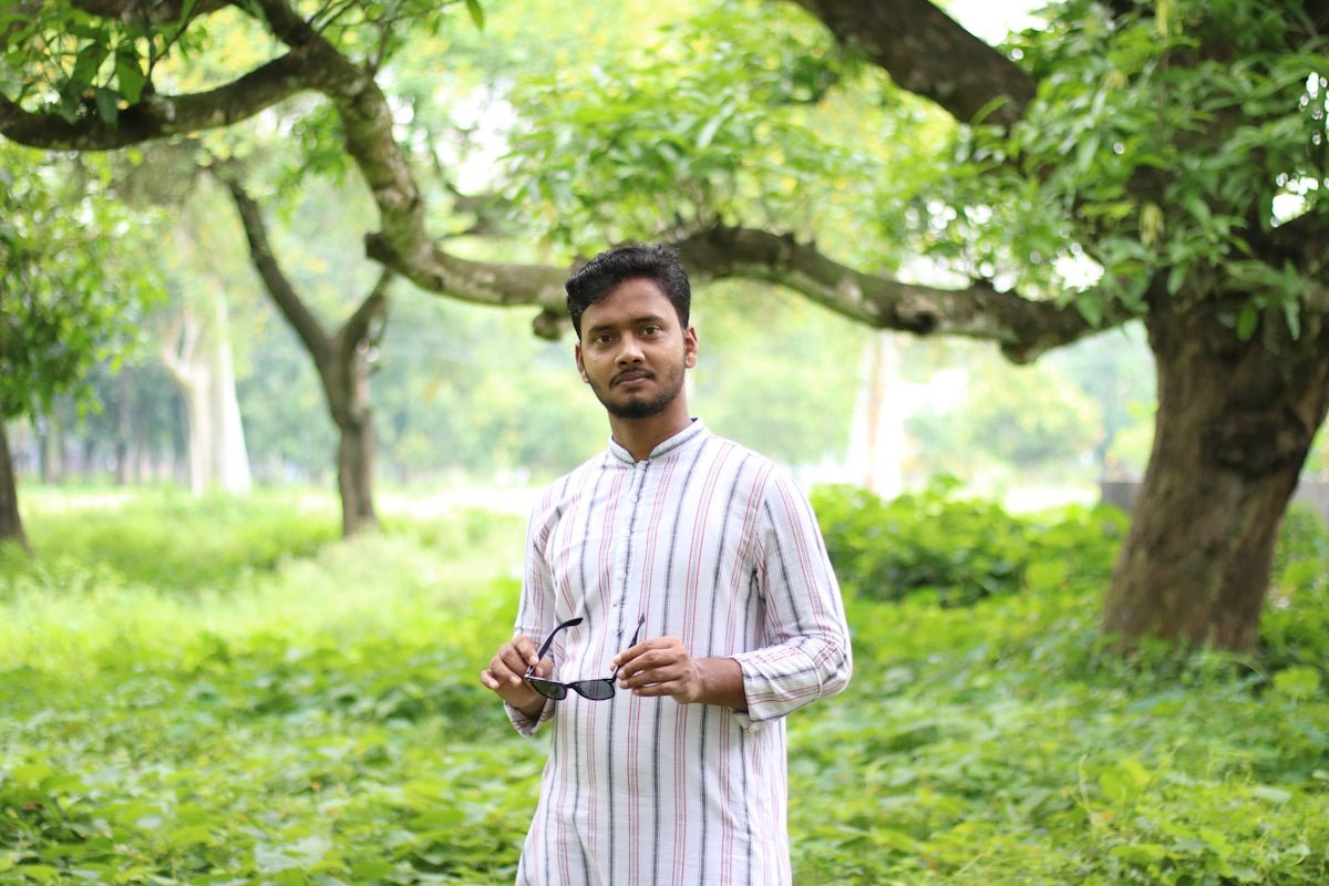 a man standing in a field holding a pair of scissors