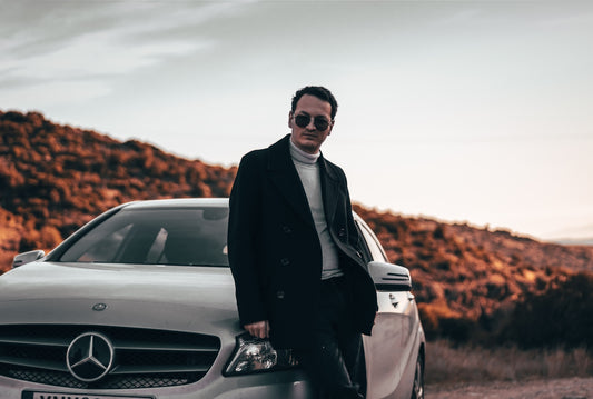 a man standing next to a car on a dirt road