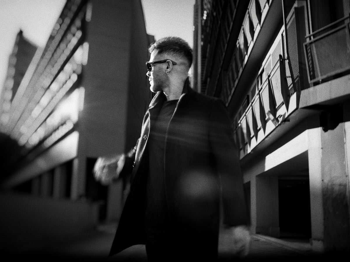 a man walking down a street next to tall buildings