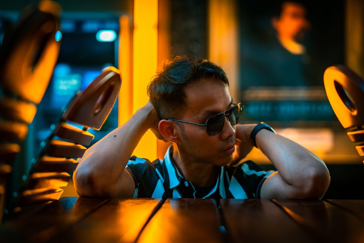 Man in sunglasses resting arms behind head