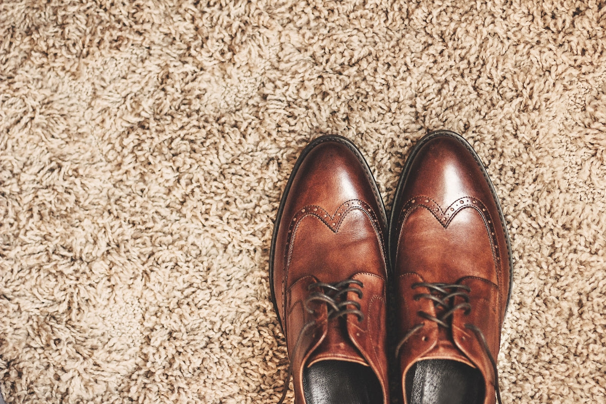 Brown leather dress shoes on a textured carpet