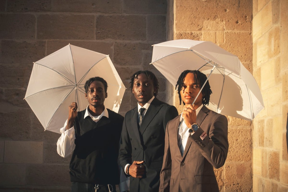 Three young men holding white umbrellas outdoors