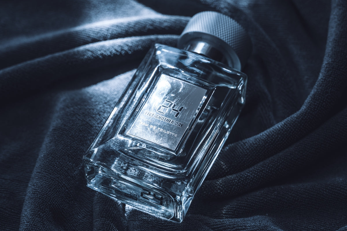 A clear glass perfume bottle on dark fabric