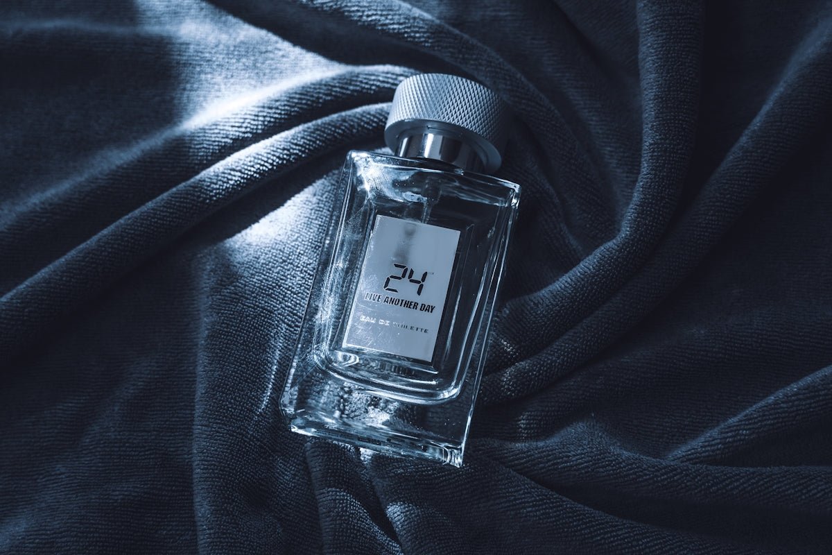 Clear glass perfume bottle on dark textured fabric.