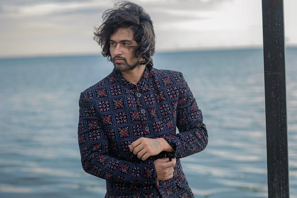 Stylish man in patterned jacket by the sea.