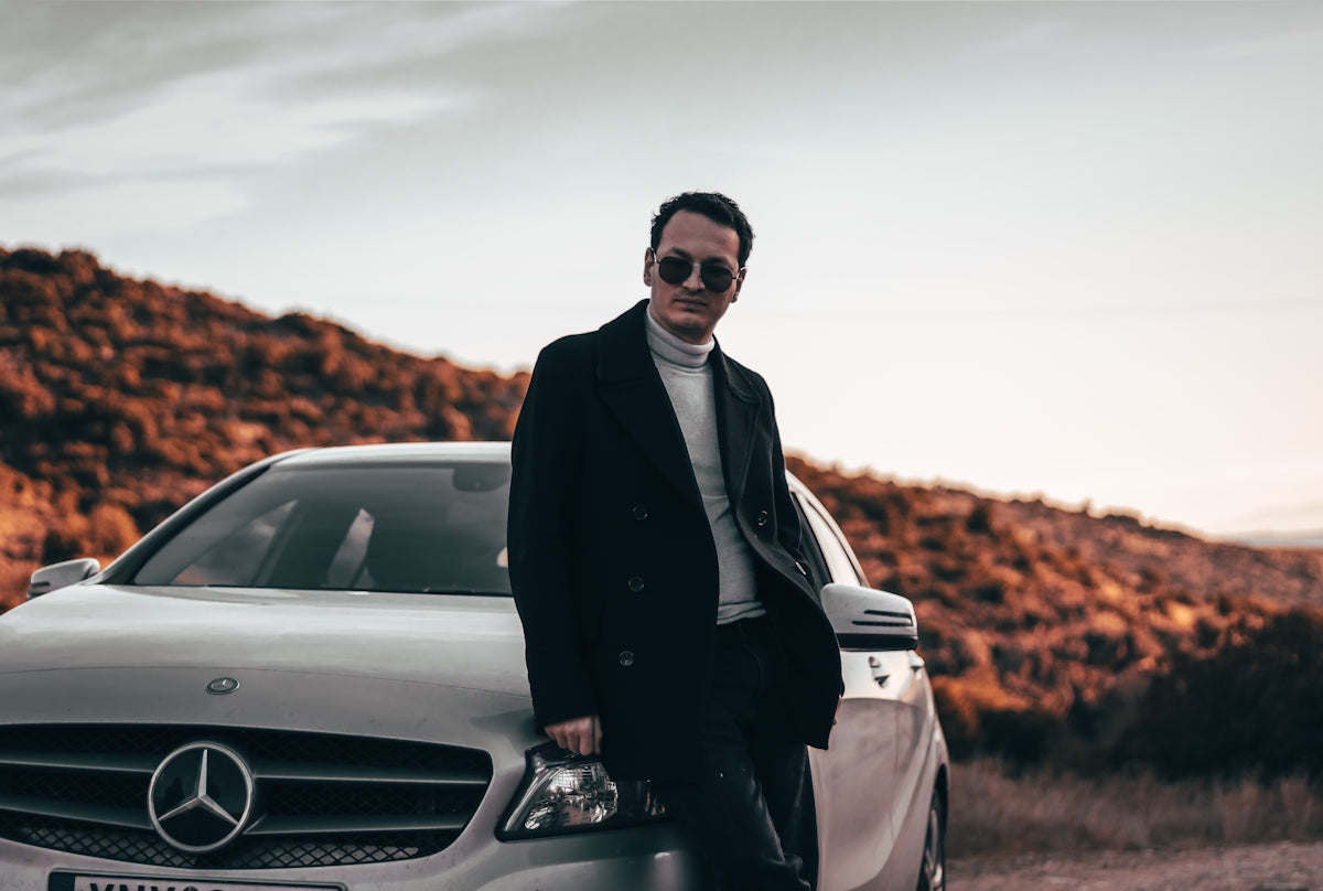 a man standing next to a car on a dirt road