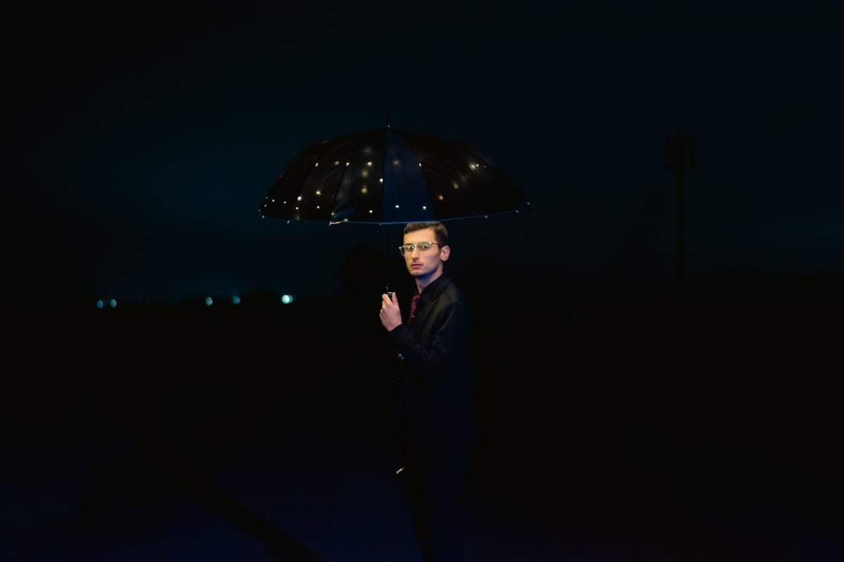 a man standing in the dark holding an umbrella