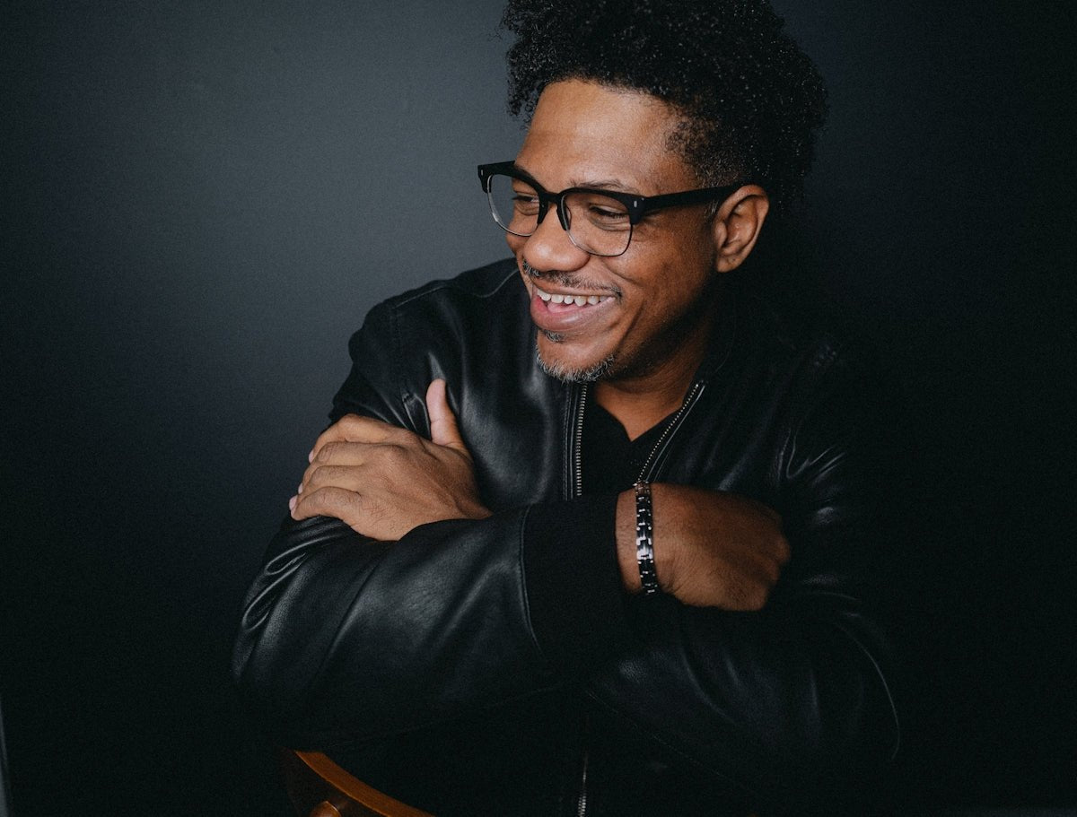 A man in a black leather jacket and glasses