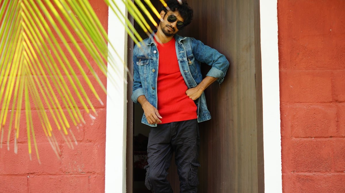 Man in denim jacket poses in doorway.