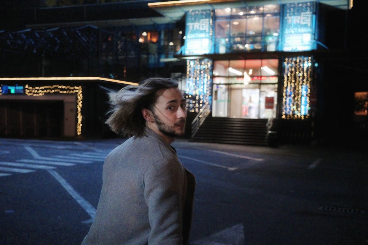 Man looks back while walking in front of a building.