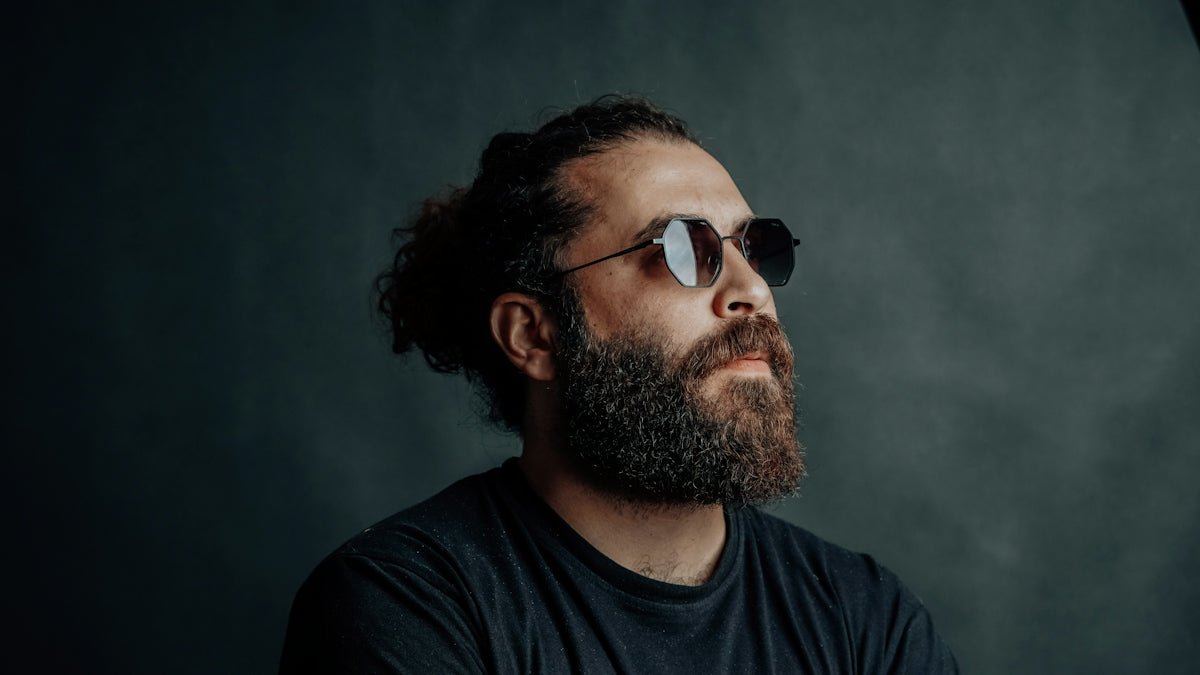 A man with a beard wears sunglasses.