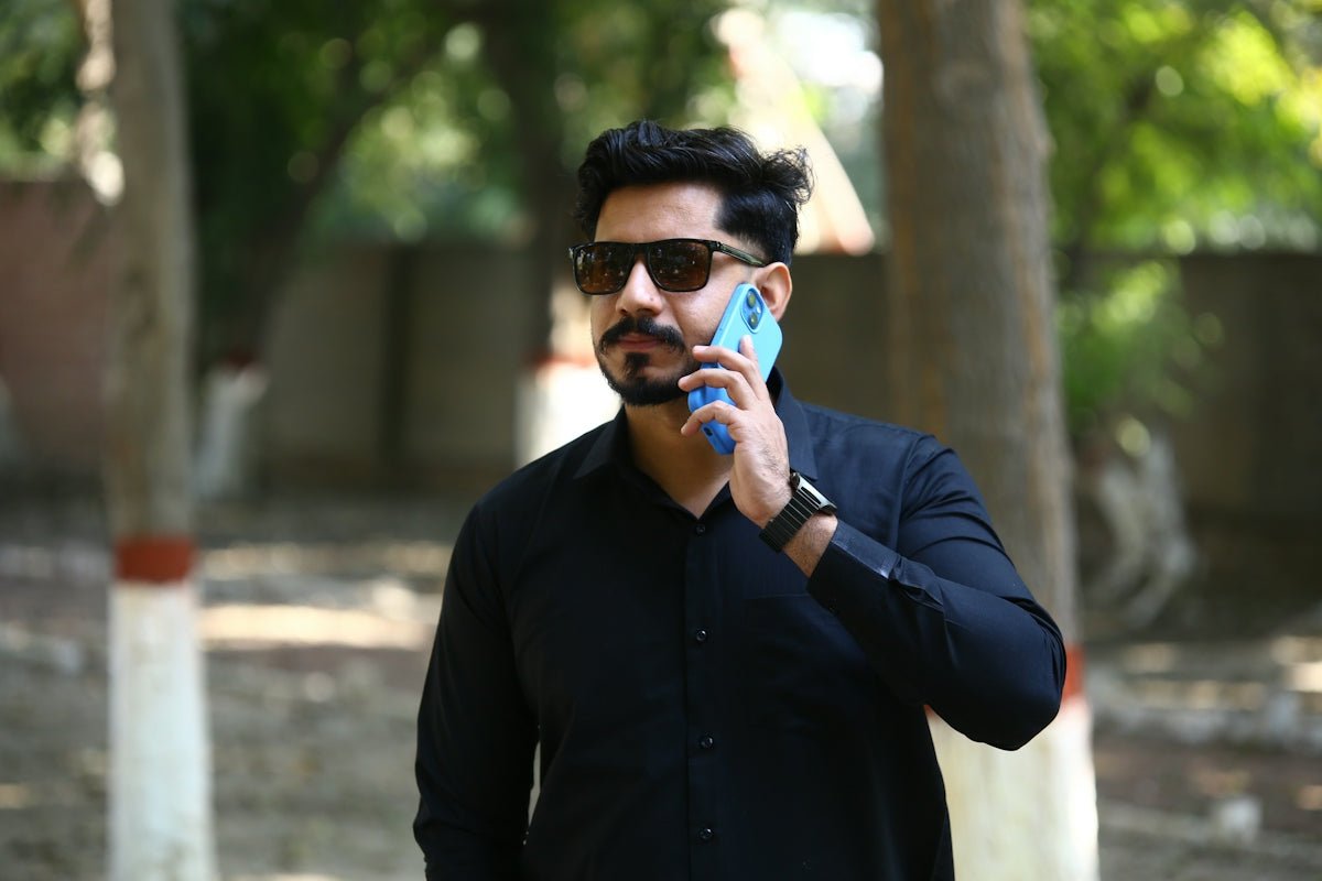 Man in black shirt talking on a blue phone