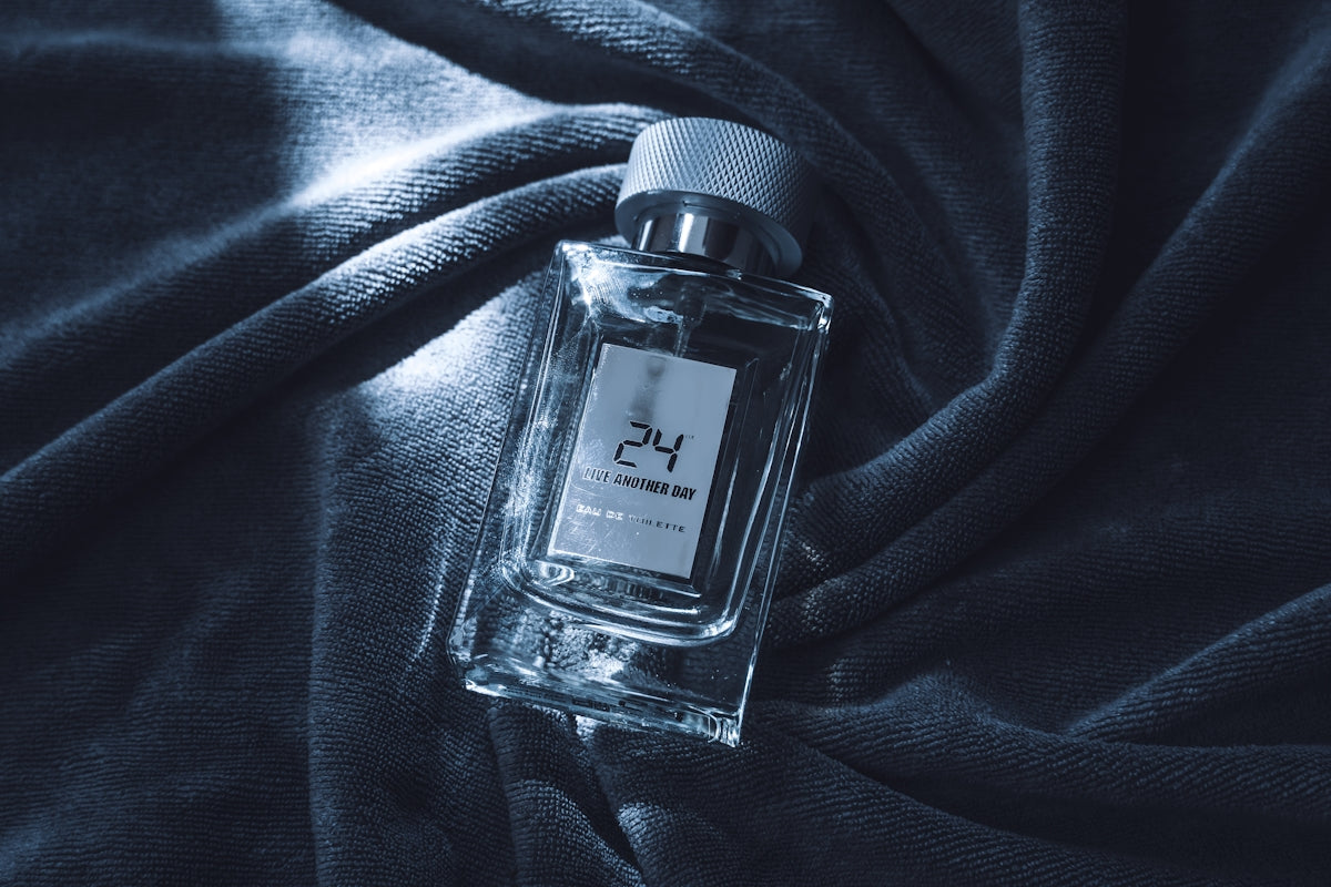 Clear glass perfume bottle on dark textured fabric.