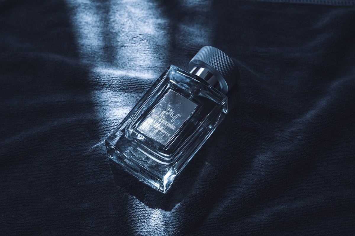 A clear glass perfume bottle with a silver cap