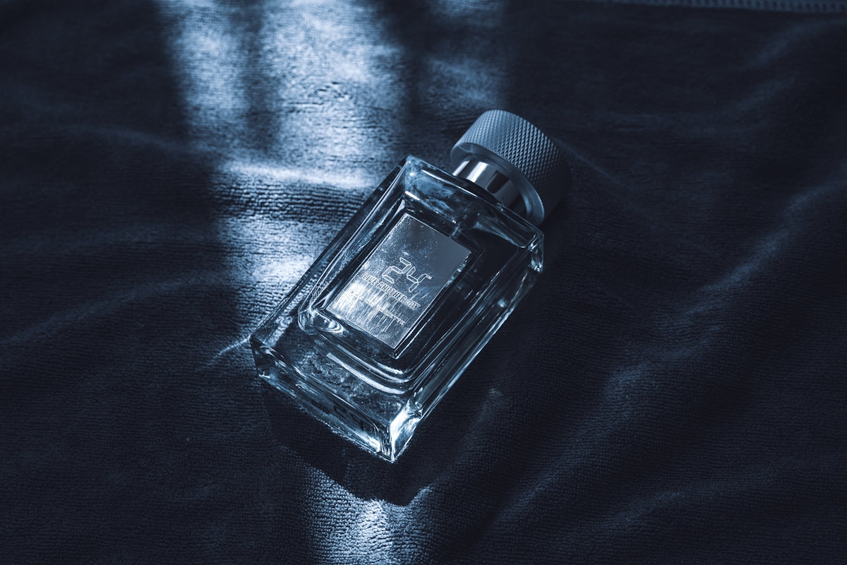A clear glass perfume bottle with a silver cap